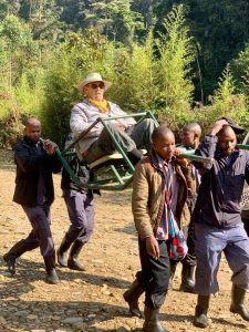 Elderly traveler using a sedan chair during gorilla trekking in Uganda