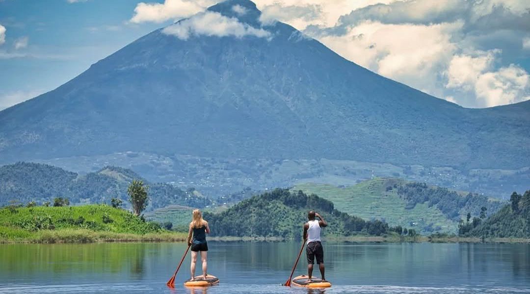 Tourists on A canoe Trip on Lake Mutanda while Enjoying Spectacular Views of Mgahinga in the background