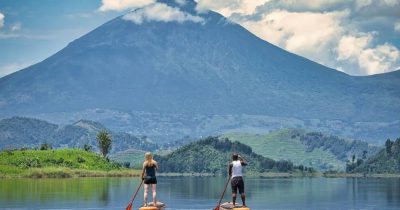 Tourists on A canoe Trip on Lake Mutanda while Enjoying Spectacular Views of Mgahinga in the background
