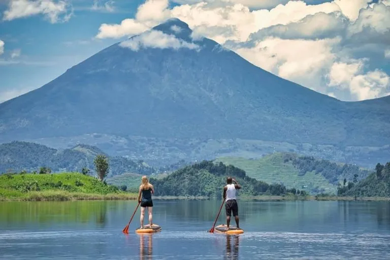 Tourists on A canoe Trip on Lake Mutanda while Enjoying Spectacular Views of Mgahinga in the background